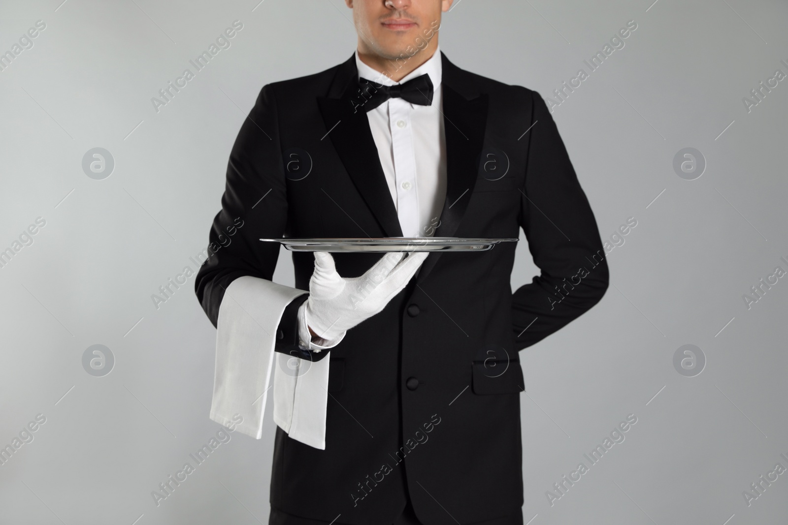 Photo of Butler with tray on light grey background, closeup