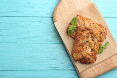 Photo of Fresh delicious puff pastry on light blue wooden table, top view. Space for text