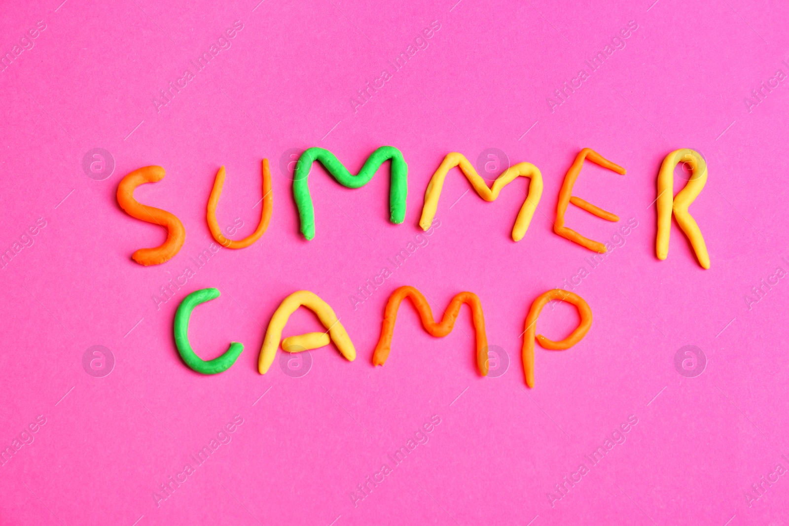 Photo of Words SUMMER CAMP made from modelling clay on color background, top view