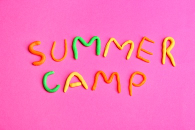 Photo of Words SUMMER CAMP made from modelling clay on color background, top view