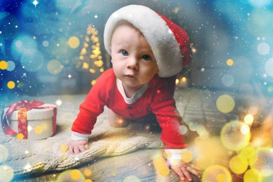 Image of Cute baby in Santa hat with Christmas gift on floor at home