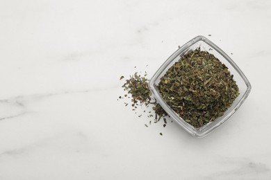 Dry tarragon in glass bowl on white table, top view. Space for text