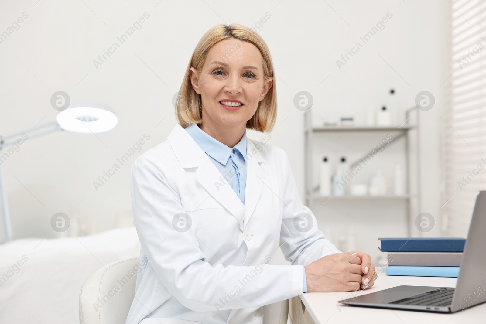 Photo of Portrait of happy dermatologist at white table in clinic