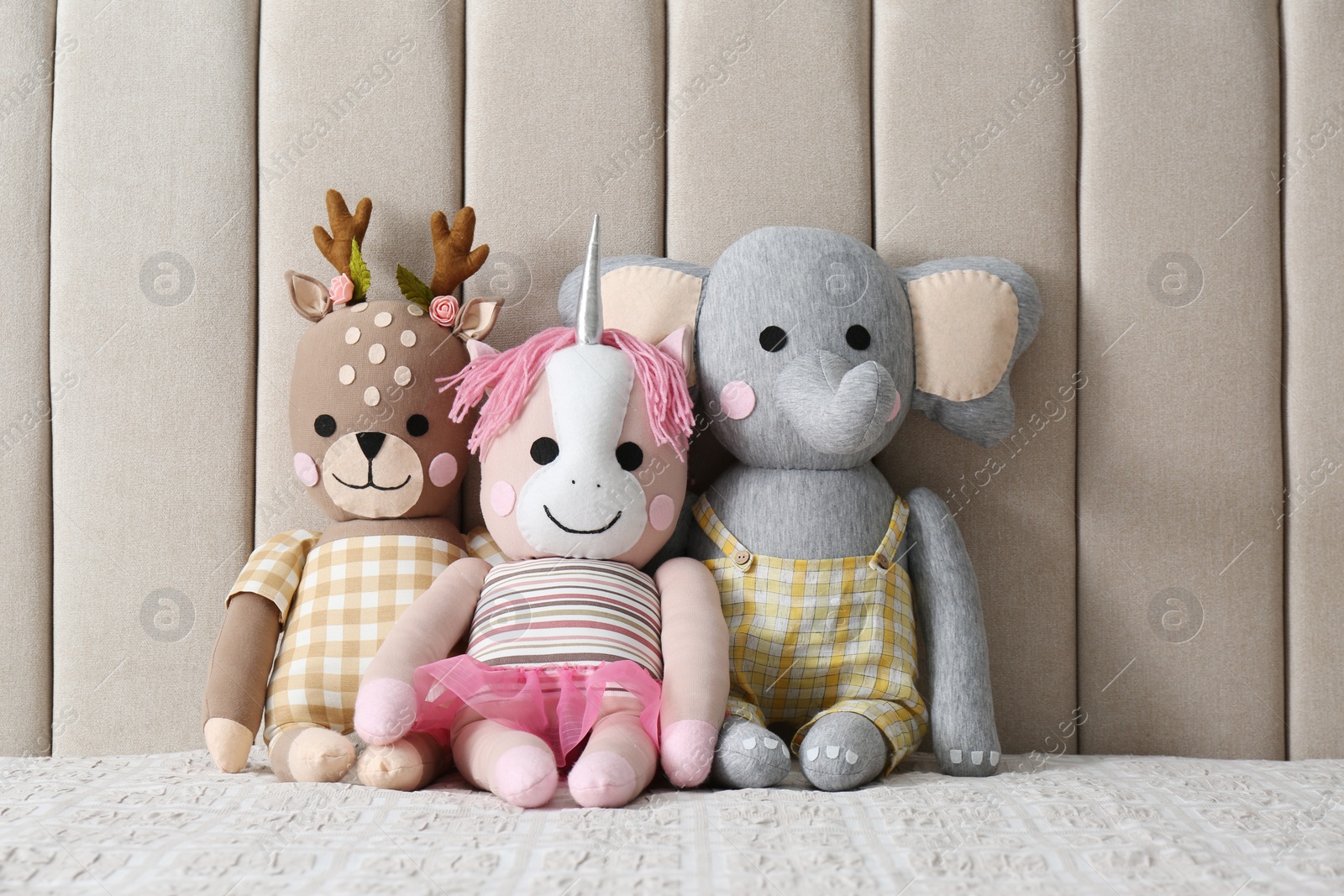 Photo of Funny toy unicorn, deer and elephant on bed. Decor for children's room interior