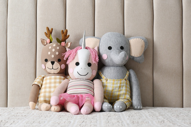 Photo of Funny toy unicorn, deer and elephant on bed. Decor for children's room interior