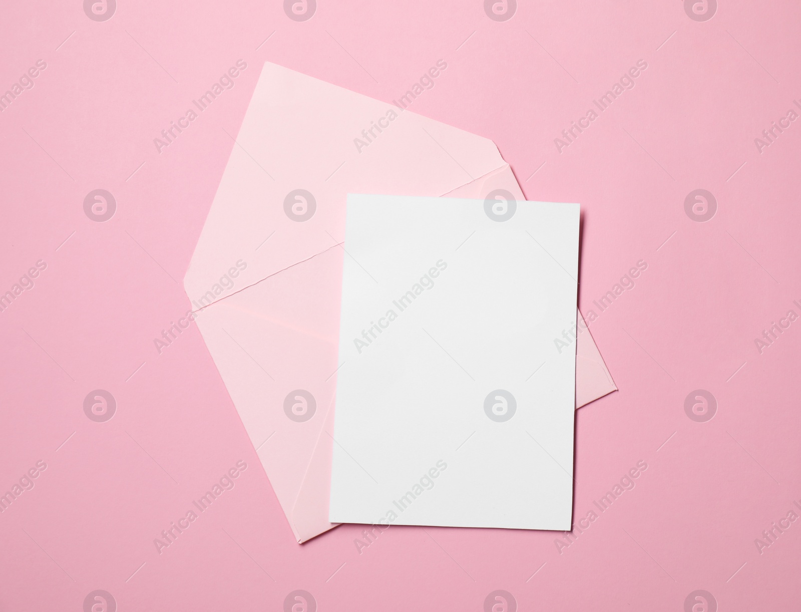 Photo of Letter envelope and card on pink background, top view