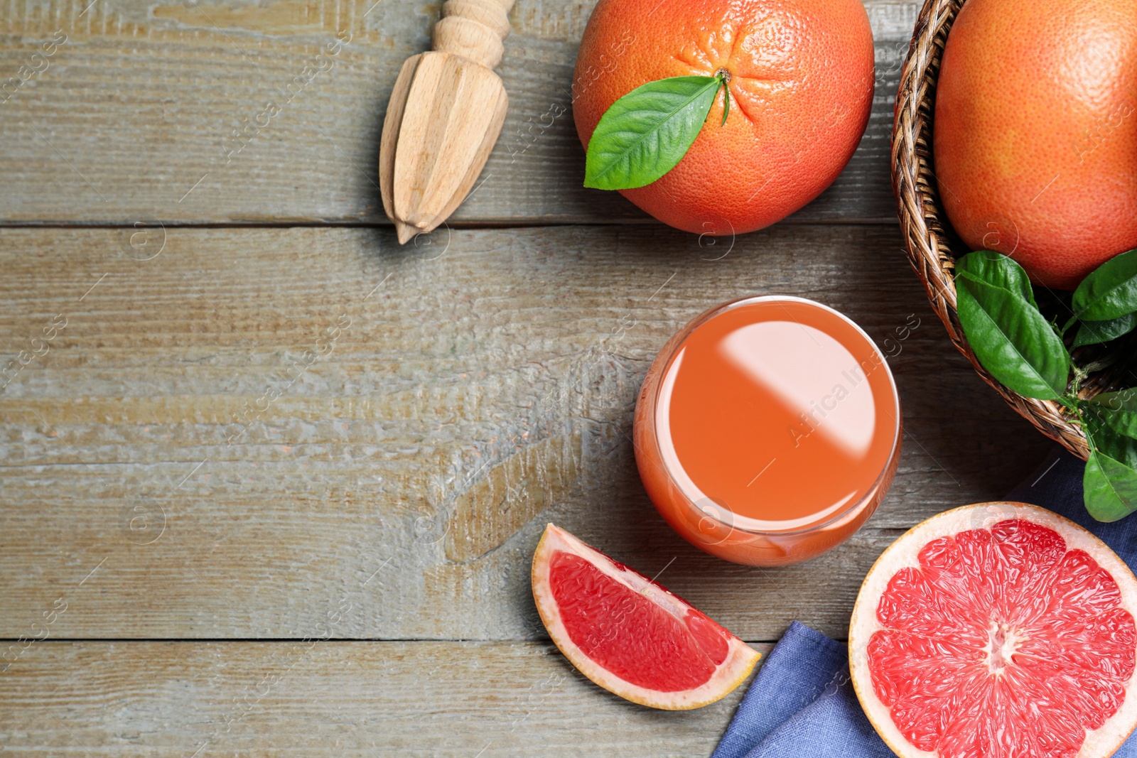 Photo of Tasty freshly made grapefruit juice and fruits on wooden table, flat lay. Space for text