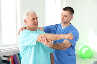 Photo of Professional physiotherapist working with senior patient in rehabilitation center