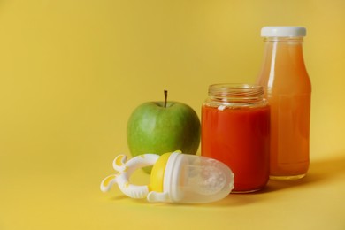 Photo of Healthy baby food, apple, juice and nibbler on yellow background, space for text