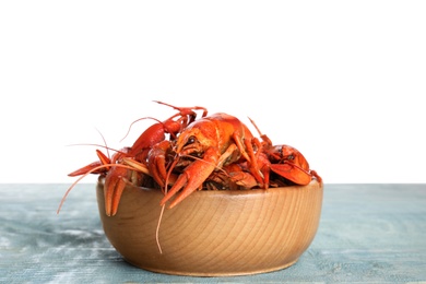 Delicious boiled crayfishes in bowl on wooden table against white background
