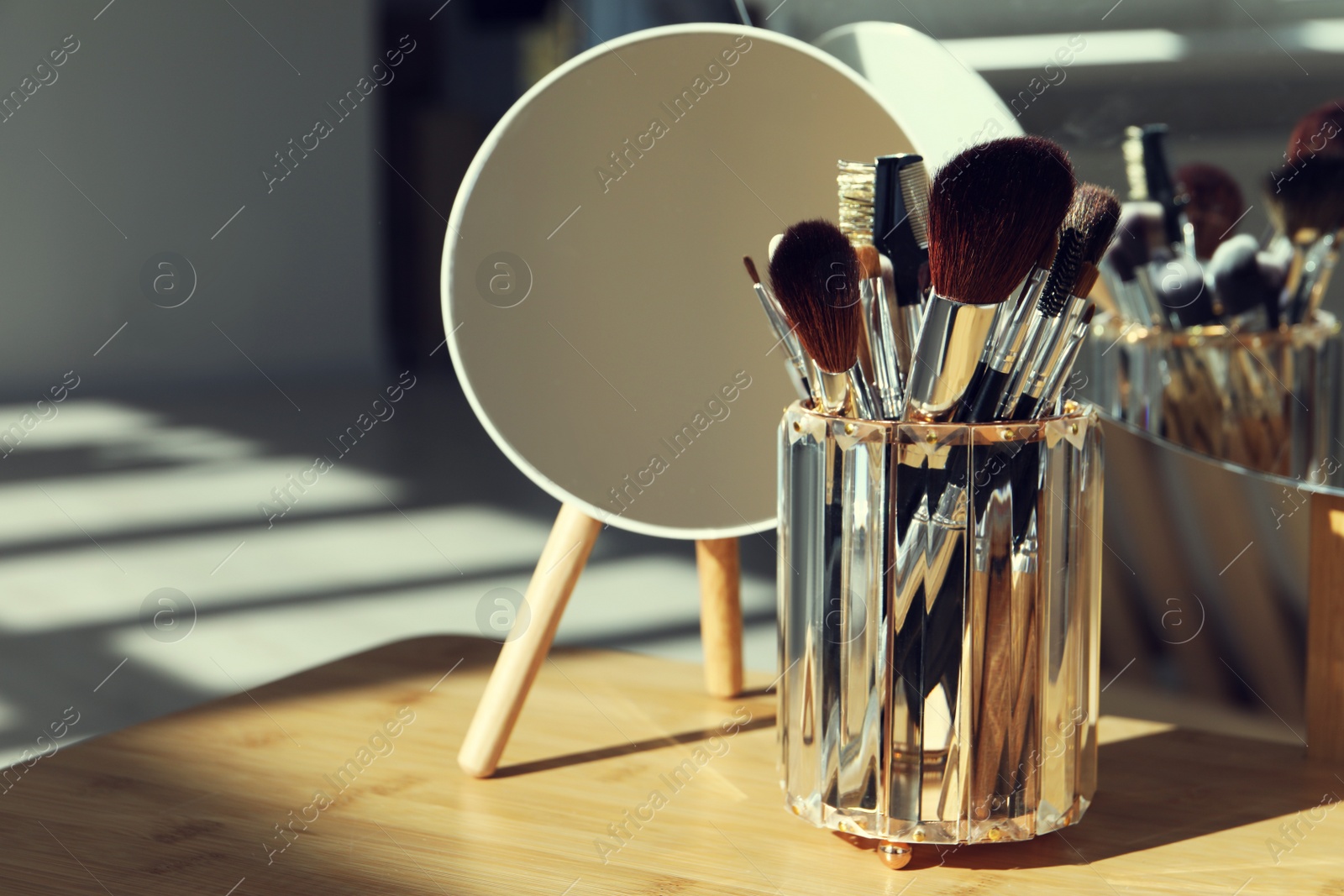 Photo of Set of professional brushes and mirror on wooden table, space for text