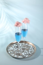 Cotton candy cocktails in glasses and confetti on light blue background