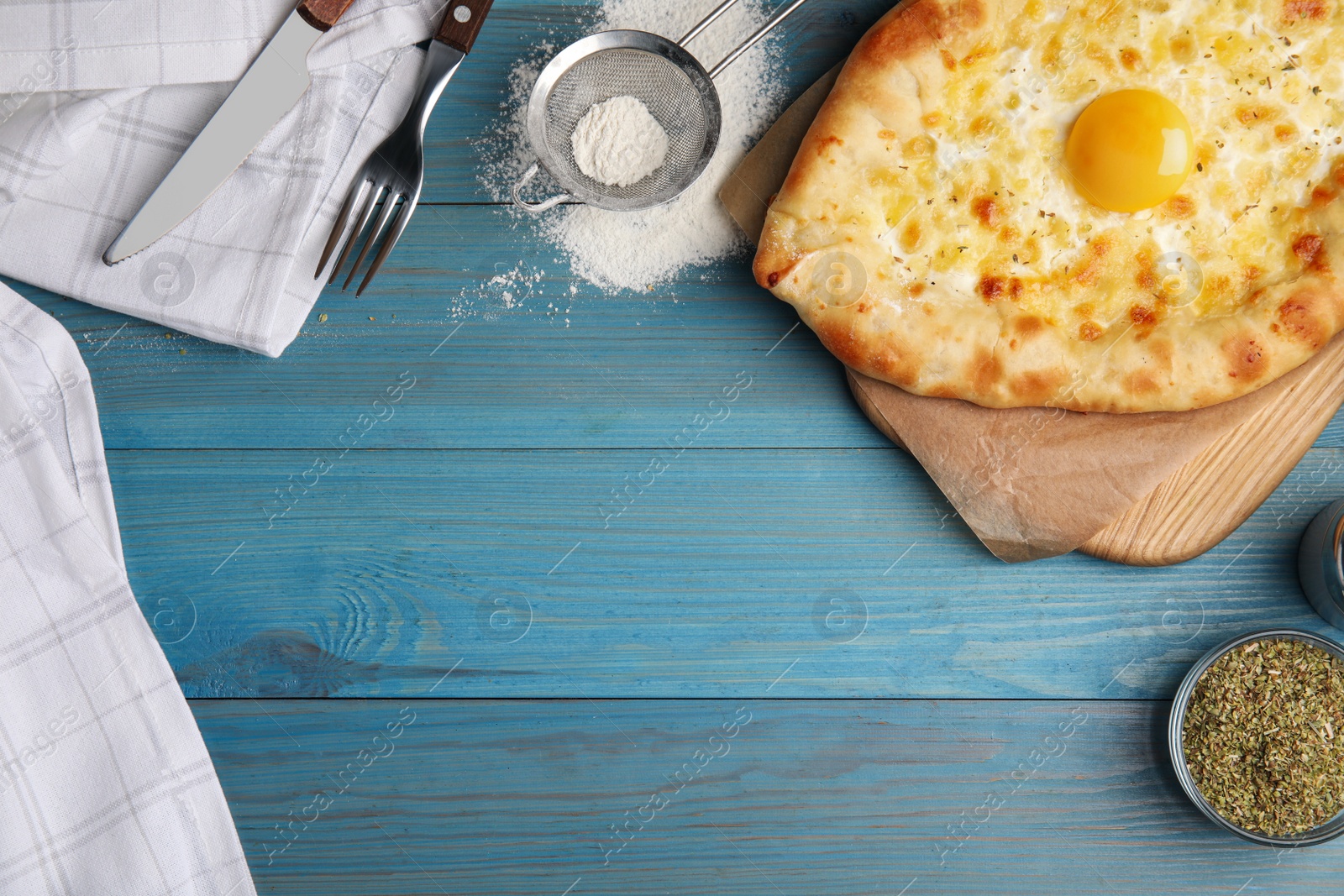 Photo of Fresh homemade khachapuri with cheese and egg served on light blue wooden table, flat lay. Space for text