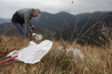 Photo of Man collecting garbage in nature, focus on plastic trash
