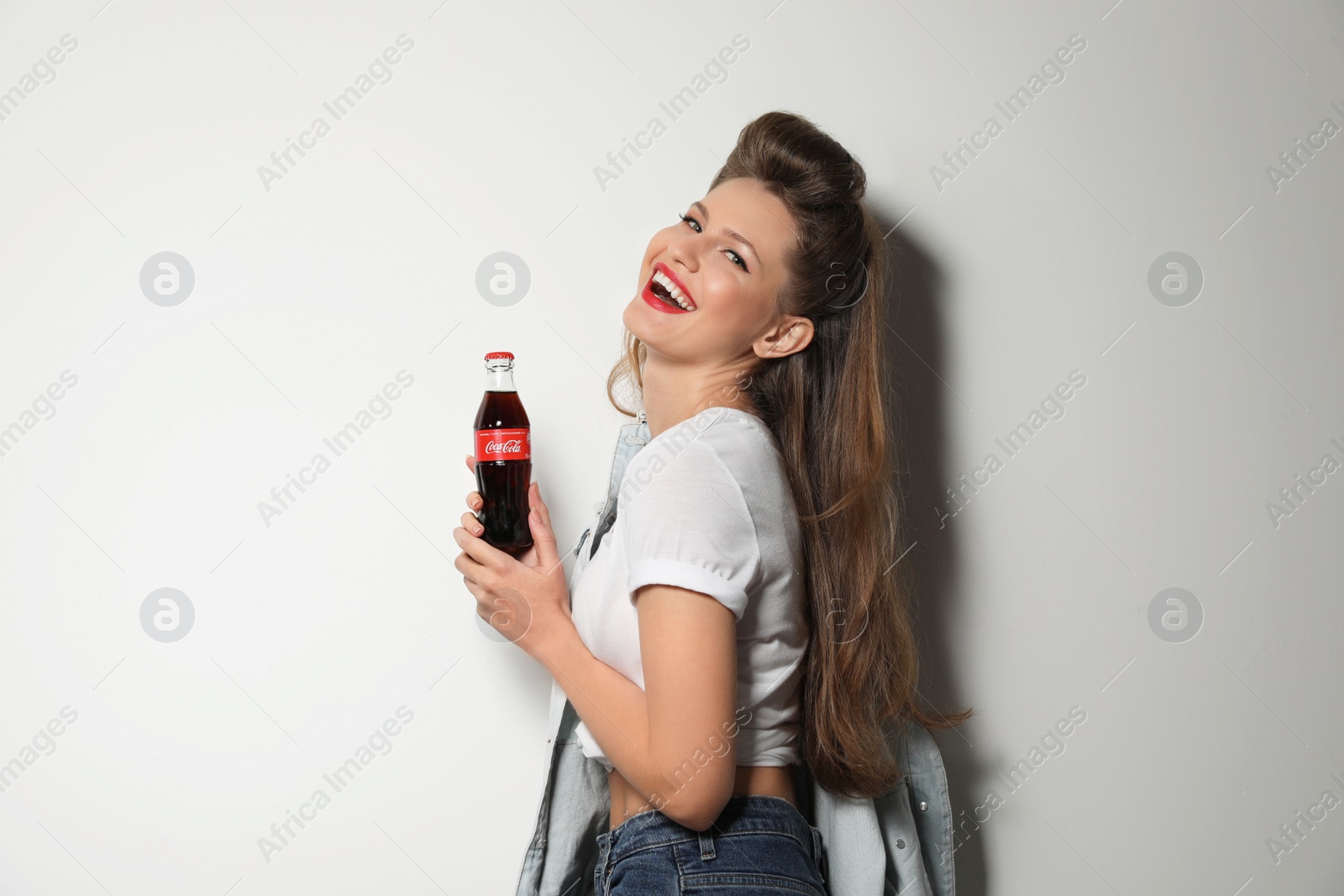 Photo of MYKOLAIV, UKRAINE - NOVEMBER 28, 2018: Young woman with bottle of Coca-Cola on white background