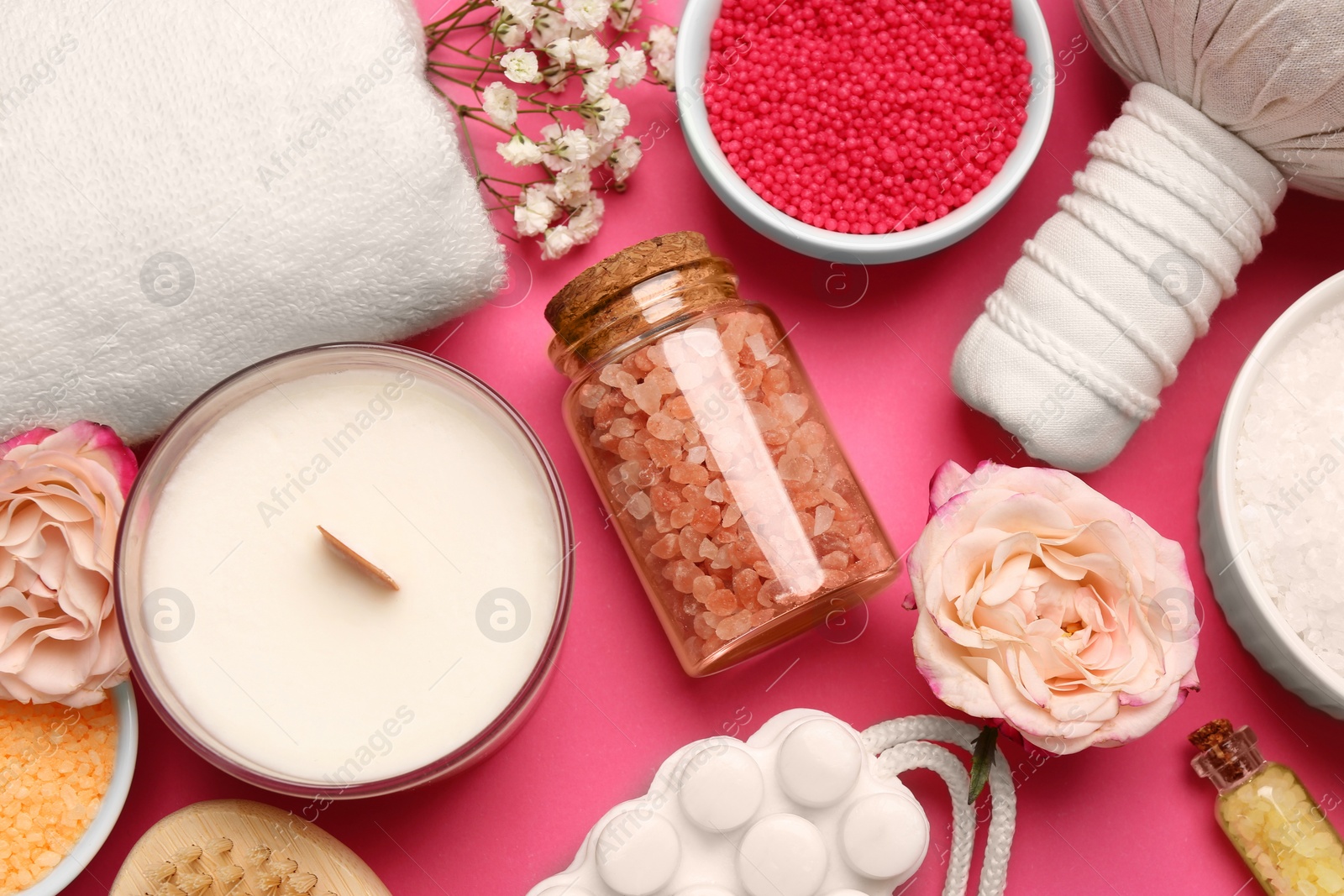 Photo of Sea salt and different spa products on pink background, flat lay