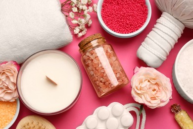 Sea salt and different spa products on pink background, flat lay