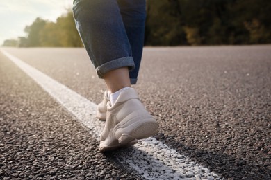 Woman going along road, closeup of legs