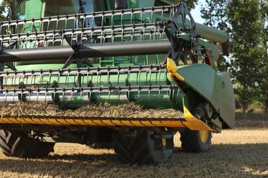 Photo of Modern combine harvester in agricultural field, closeup