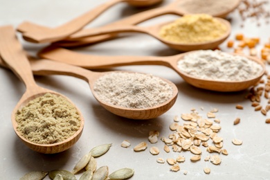 Spoons with different types of flour on table