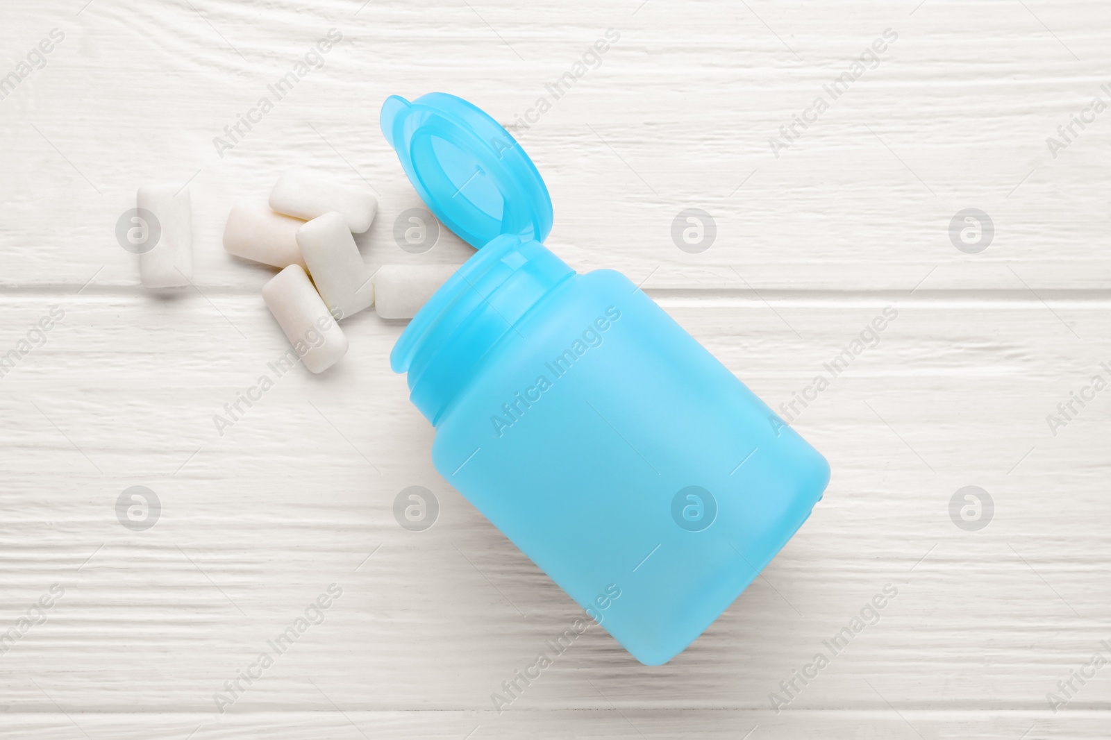 Photo of Jar with chewing gums on white wooden table, flat lay