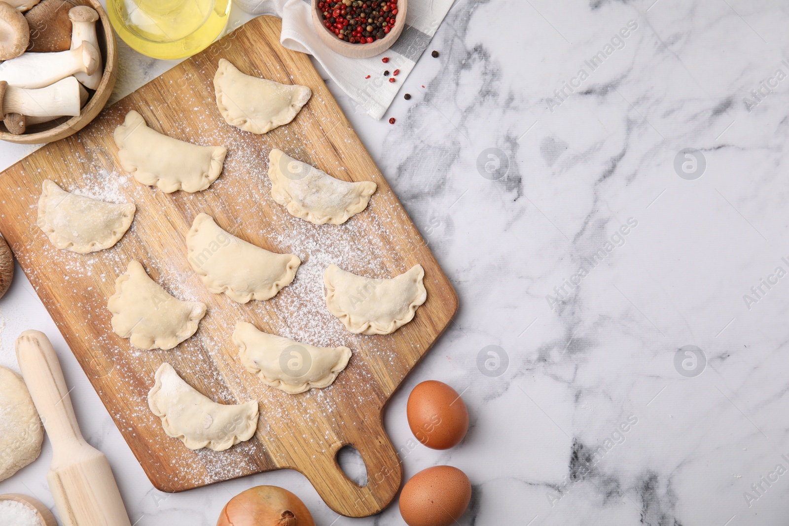 Photo of Process of making dumplings (varenyky) with mushrooms. Raw dough and ingredients on white marble table, flat lay. Space for text