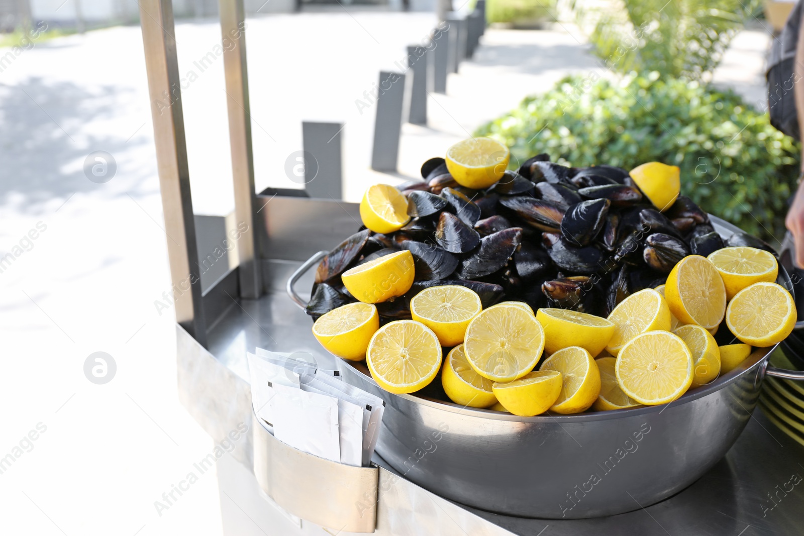 Photo of Stewpan with fresh mussels and lemons on table