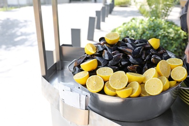 Stewpan with fresh mussels and lemons on table