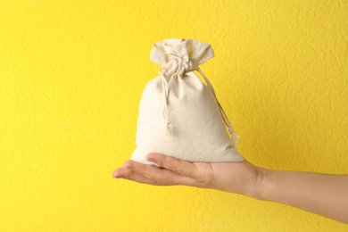Photo of Woman holding full cotton eco bag on yellow background, closeup