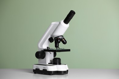 Photo of Modern microscope on table against green background