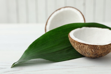 Composition with halves of coconut on white wooden background