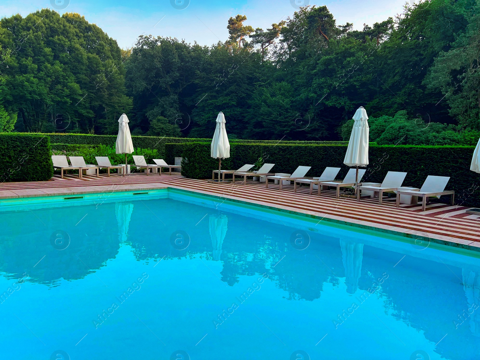 Photo of Outdoor swimming pool in luxury hotel on sunny summer day. Time for relax