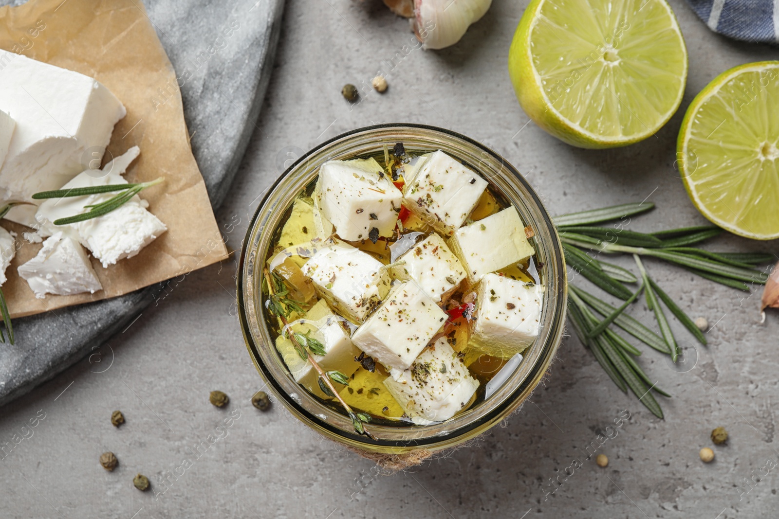 Photo of Flat lay composition with pickled feta cheese in jar on grey table