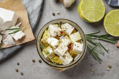 Flat lay composition with pickled feta cheese in jar on grey table