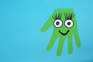 Photo of Funny green hand shaped monster on light blue background, top view with space for text. Halloween decoration