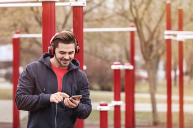 Photo of Young man with headphones listening to music on sports ground