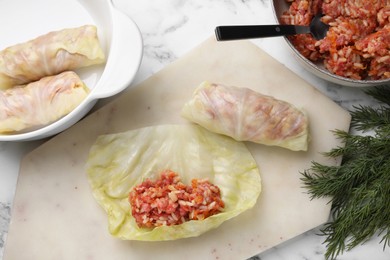 Preparing stuffed cabbage rolls on white marble table, flat lay