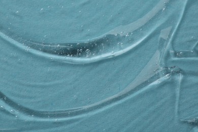 Clear cosmetic serum on light blue background, macro view