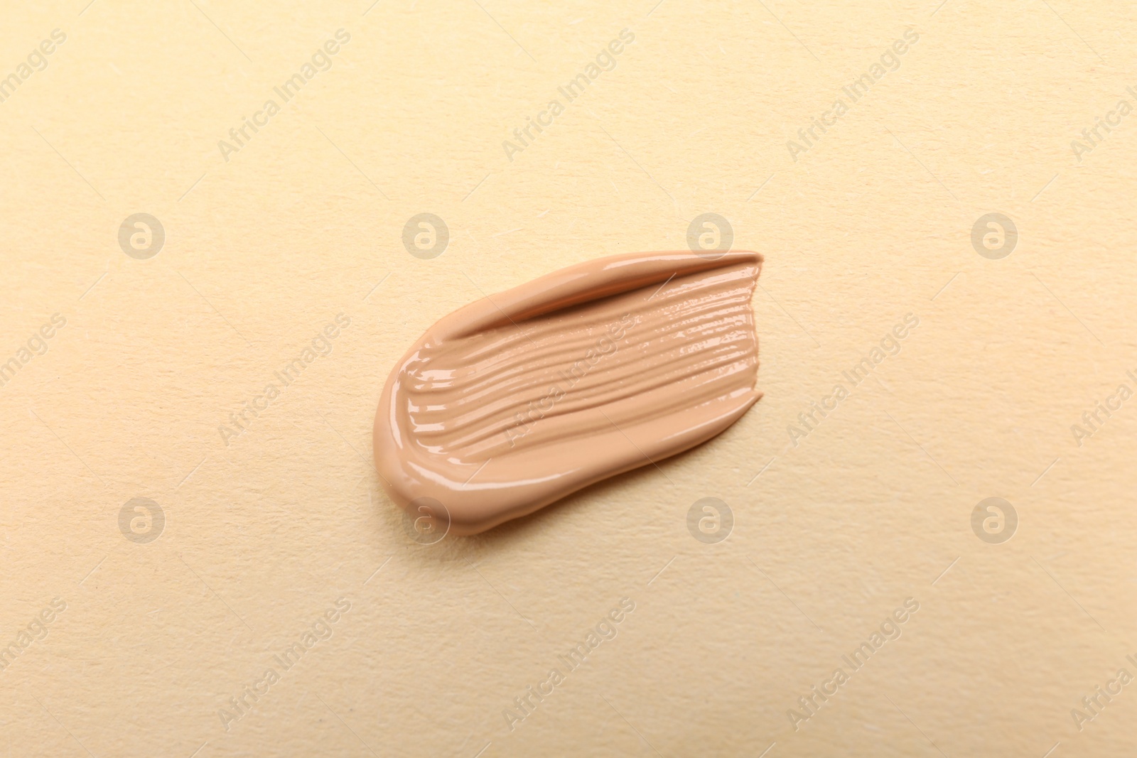 Photo of Smear of skin foundation on beige background, top view