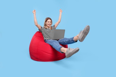 Photo of Emotional woman with laptop sitting on beanbag chair against light blue background