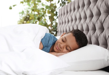 Photo of Cute little African-American boy sleeping in bed