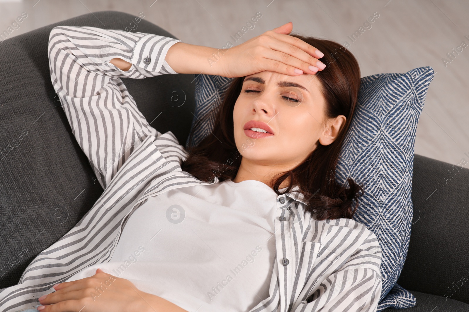 Photo of Young woman suffering from headache indoors. Hormonal disorders