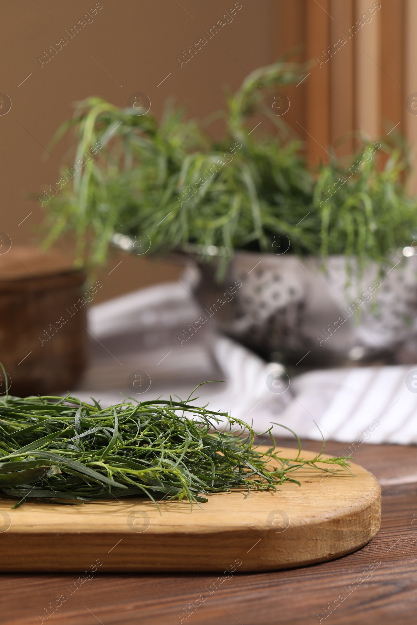 Photo of Board with fresh tarragon leaves on wooden table, closeup