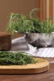 Board with fresh tarragon leaves on wooden table, closeup