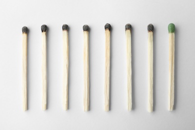 Photo of Row of burnt matches and whole one on white background, top view. Uniqueness concept