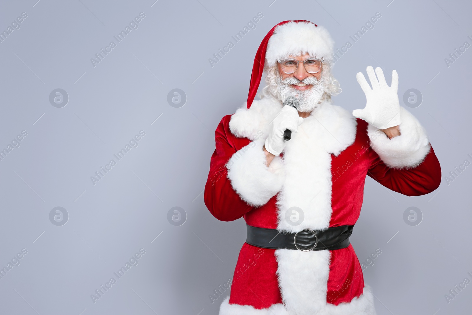 Photo of Santa Claus singing into microphone on color background. Christmas music