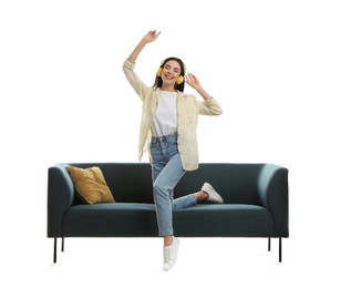 Young woman listening to music on comfortable green sofa against white background