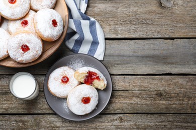 Photo of Delicious jelly donuts served with milk on wooden table, flat lay. Space for text