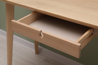 Photo of Stylish desk with open empty drawer in office, closeup