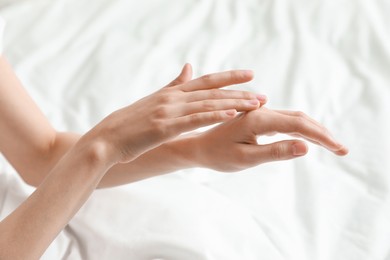 Woman applying hand cream in bed, closeup